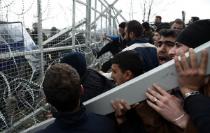 Flüchtlinge versuchen den Zaun einzureißen, damit sie die Grenze überqueren können.